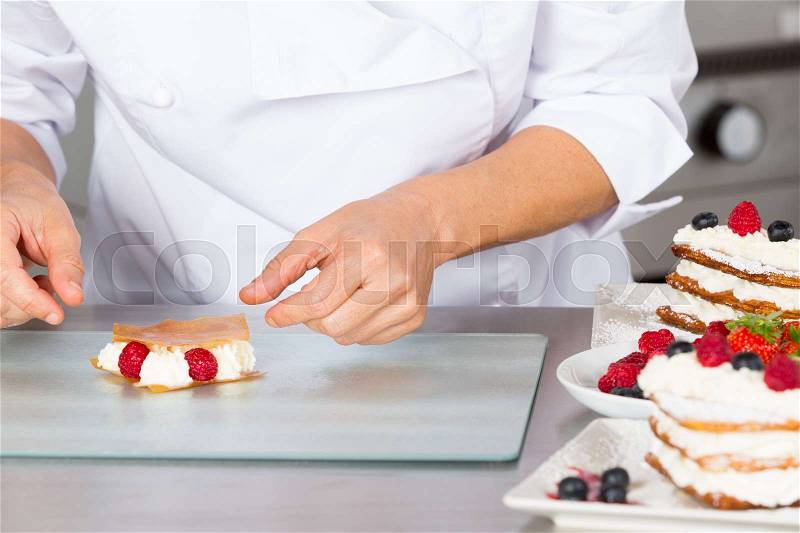 Pastry chef finishing a delicious puff pastry, stock photo