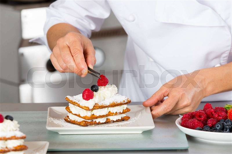 Pastry chef decorating with berries pie pastry, stock photo