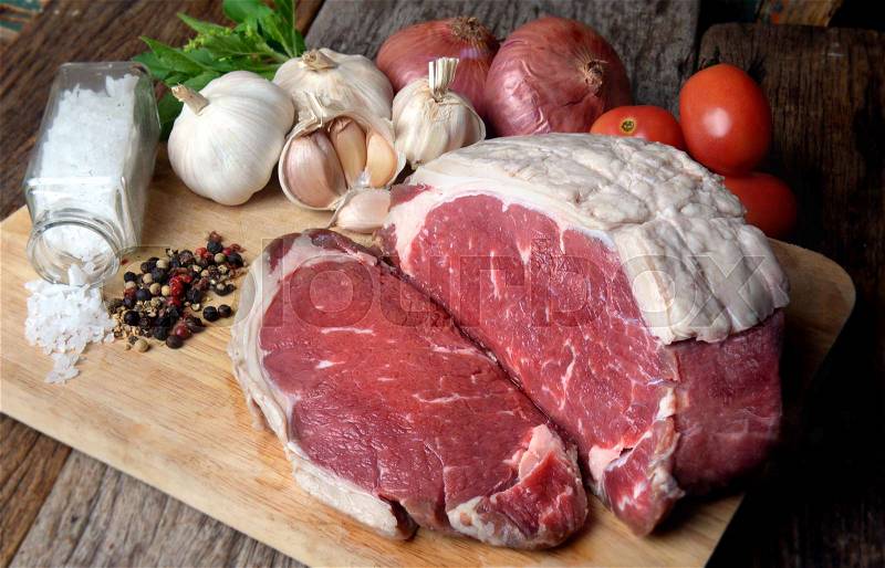 Rare Angus beef cut and ready for cooking display with seasoning and vegetable ingredient photo in studio lighting, stock photo