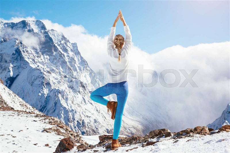 Young woman practicing yoga pose outdoors in winter. Streching workout in snow on top of mountain. Hiking in cold season. Calm and silent view, stock photo