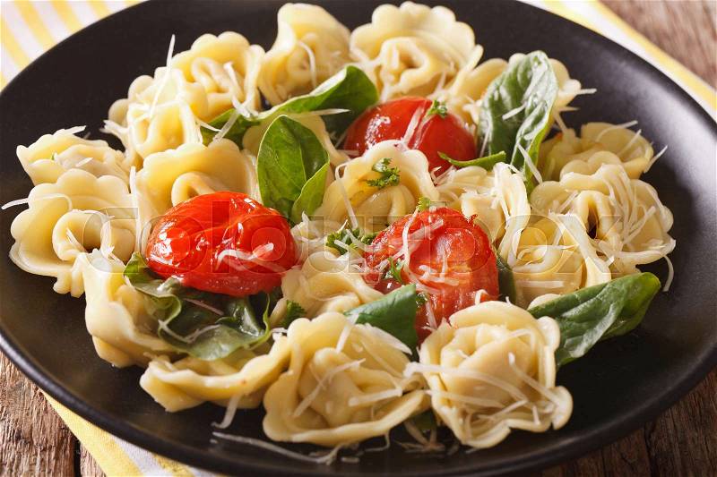 Italian cuisine: tortellini with spinach, tomatoes and parmesan close-up on a plate. horizontal , stock photo