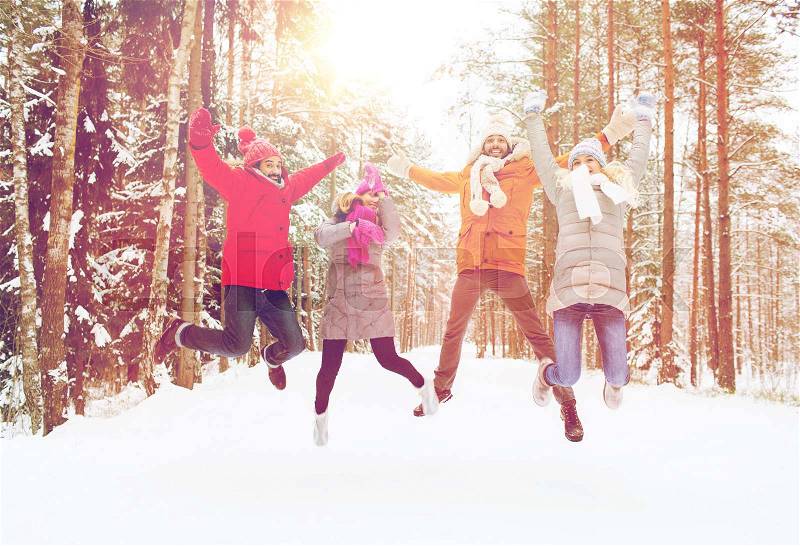 Leisure, season, friendship and people concept - group of smiling men and women having fun and jumping in winter forest, stock photo