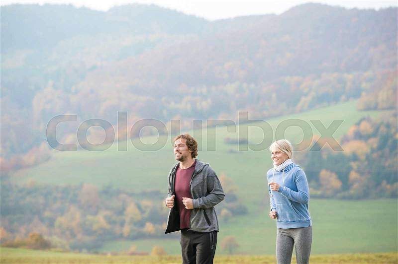 Beautiful young couple running in colorful sunny autumn nature, stock photo