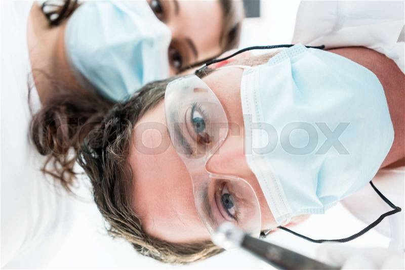 Dentist and nurse in treatment from patient point of view, stock photo