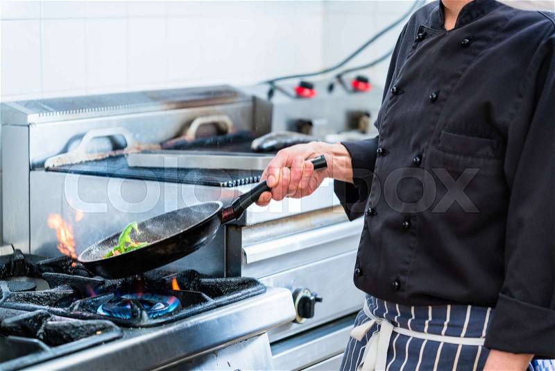 Chef roasting vegetables in restaurant kitchen, stock photo