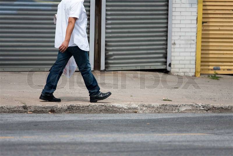 One man walking down the sidewalk along the side of the road, stock photo