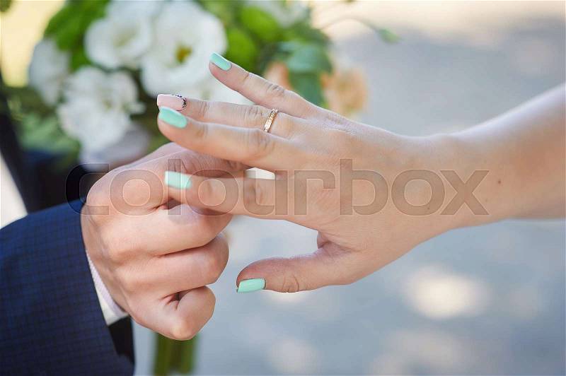 Groom wears bride a wedding ring on the finger, stock photo