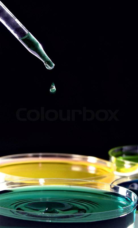 Laboratory pipette filled with green liquid and drop of chemical above test tubes, stock photo