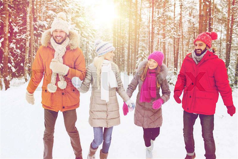 Love, relationship, season, friendship and people concept - group of smiling men and women walking ad having fun in winter forest, stock photo