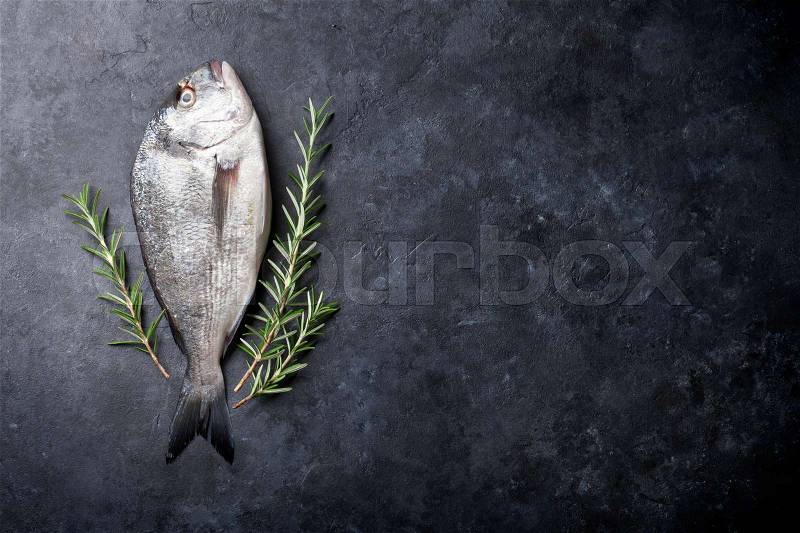 Raw fish cooking and ingredients. Dorado and rosemary herb. Top view with copy space on stone table, stock photo