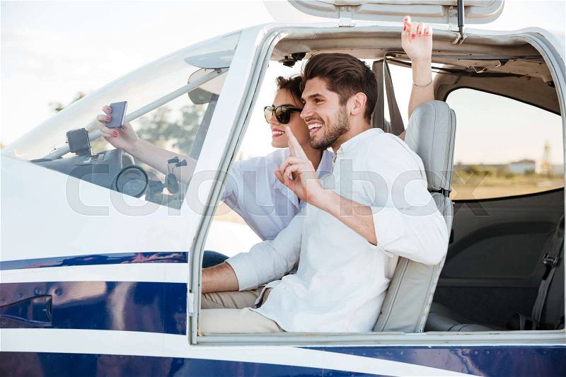 Happy smiling couple making selfie inside plane cabin after landing, stock photo