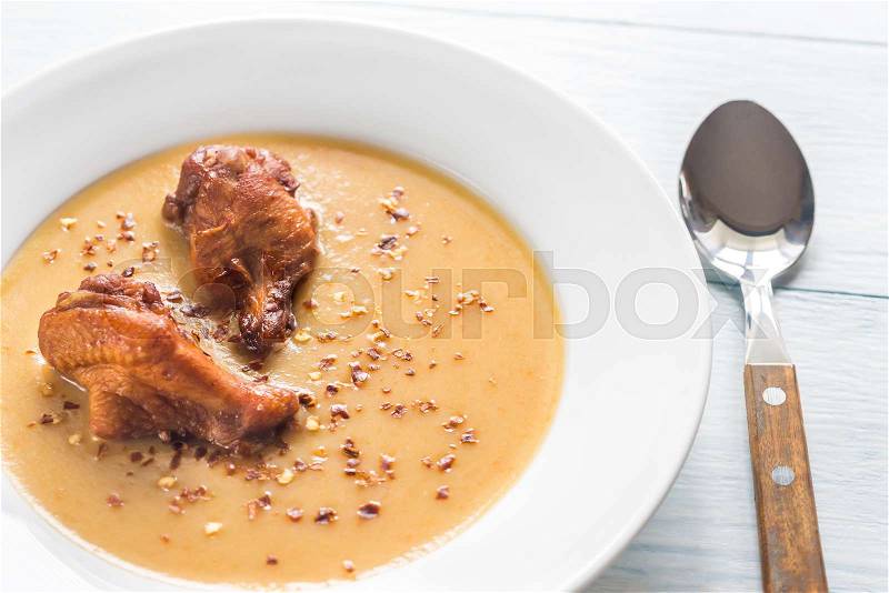 Portion of pea cream soup with smoked chicken wings, stock photo