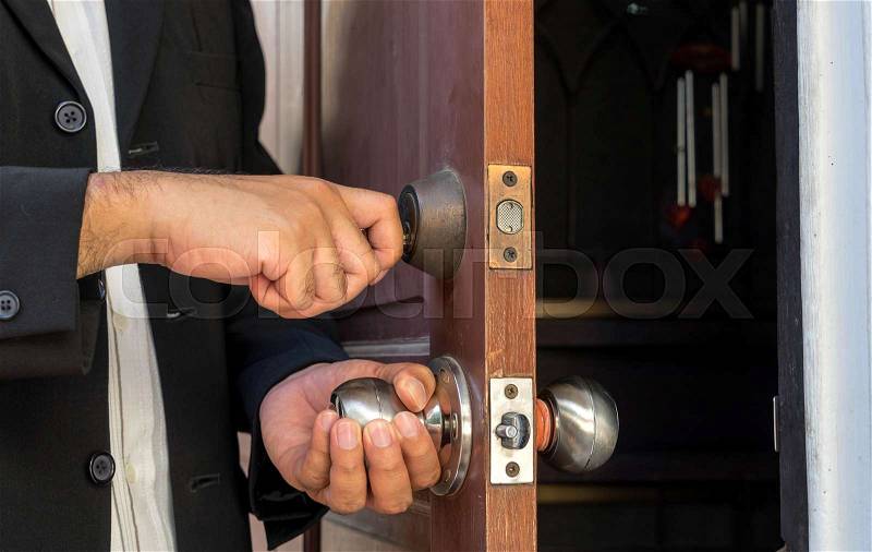 Salesman in black suit open the door by key for welcome customer, stock photo