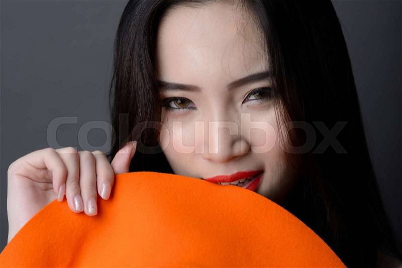Portrait close up of beautiful asian red lips woman model bite a orange striped hat, stock photo