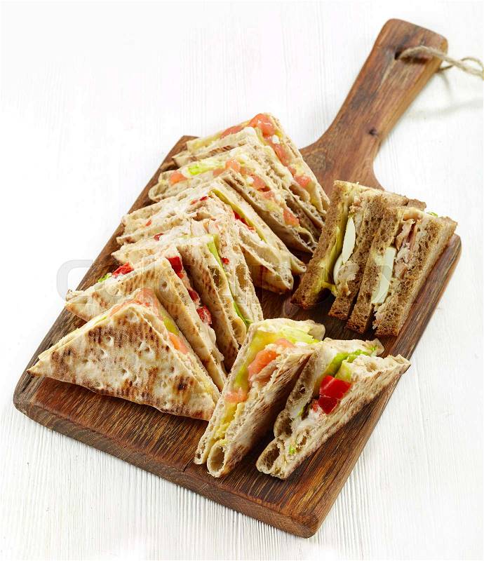 Various triangle sandwiches on wooden cutting board, stock photo