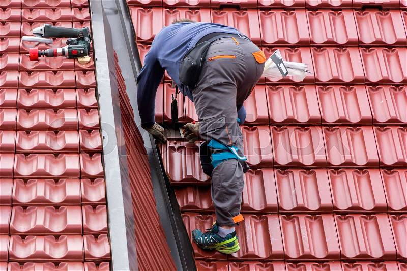 Roofer repair the roof of clay tiles, stock photo
