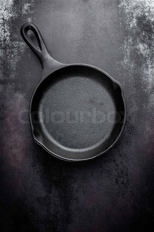 Cast iron pan on black metal culinary background, view from above, stock photo