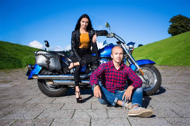 Young man and woman posing with blue vintage motorbike, stock photo