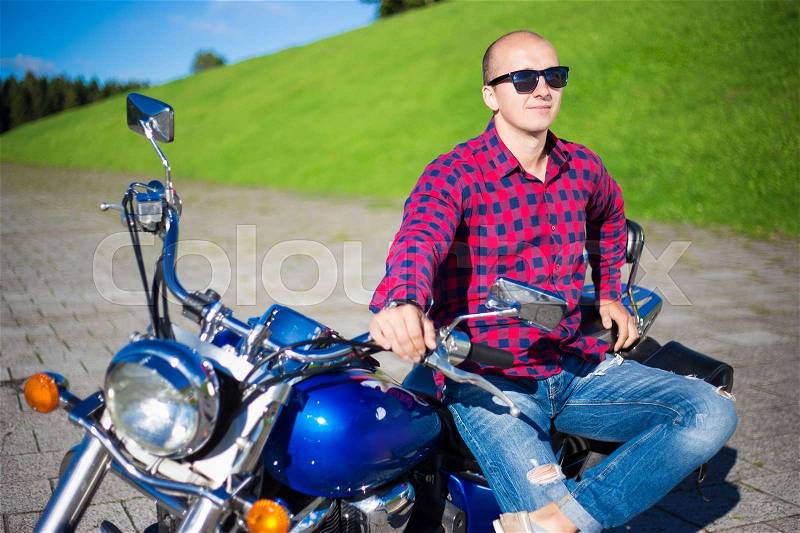 Young handsome man posing with beautiful retro motorcycle, stock photo