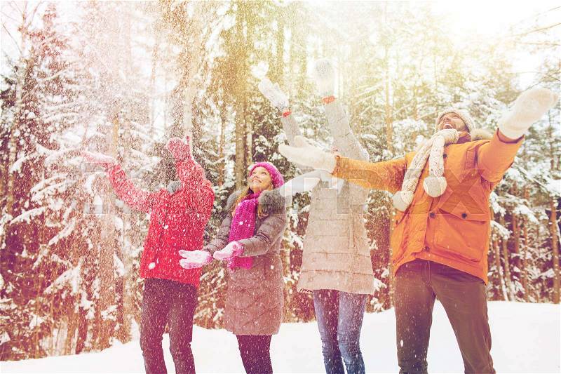 Love, relationship, season, friendship and people concept - group of smiling men and women having fun and playing with snow in winter forest, stock photo