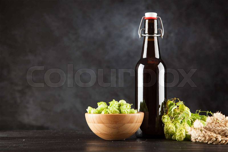 Beer bottle with malt and hops, dark background, stock photo
