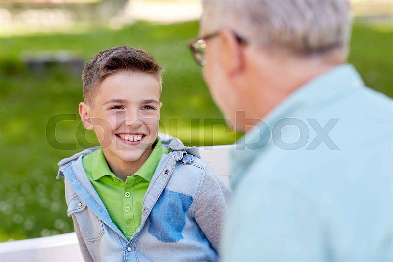 Family, generation, communication and people concept - happy grandfather and grandson talking at summer park, stock photo