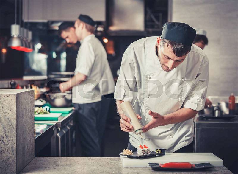 Male cooks preparing sushi in the restaurant kitchen, stock photo