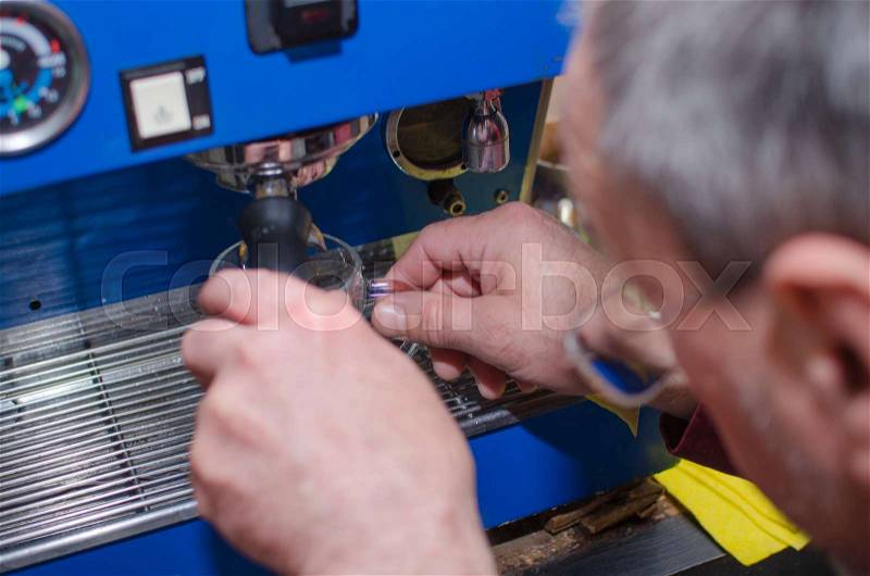 Aged man making coffee with coffee machine, stock photo