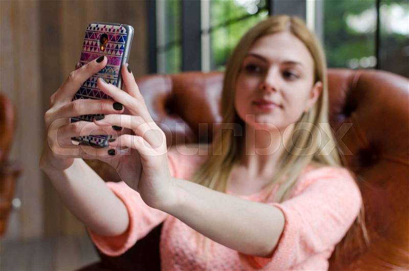 Young girl is making selfie with her colored phone, stock photo