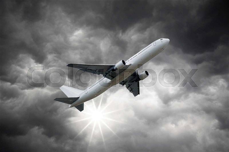 Airplane above the Sun shining from Darkclouds of storm sky, stock photo