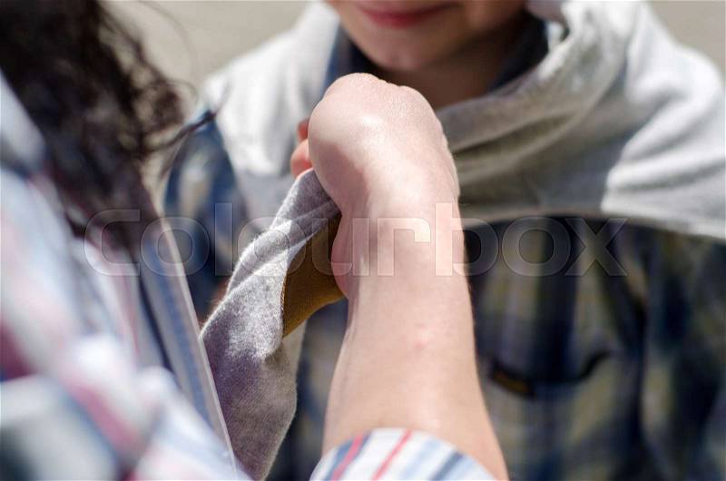 Young mother dressing up her young son, stock photo