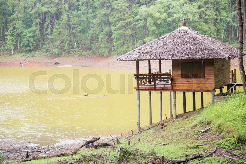 Small house on the edge of the reservoir. On the mound behind a forest, stock photo