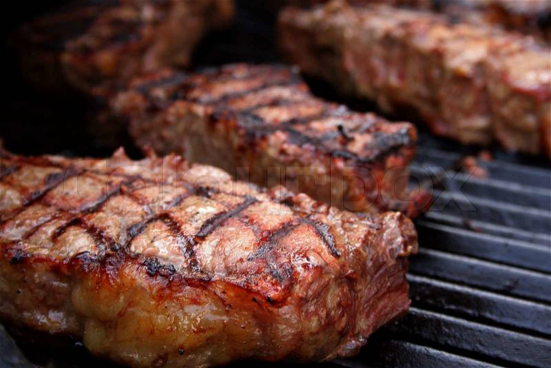 Thick, juicy steaks on a barbecue grill, stock photo