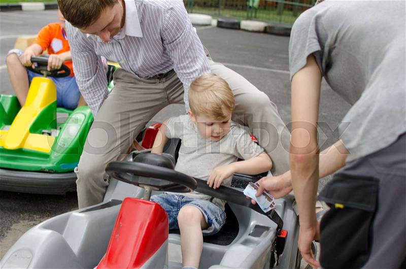Small baby boy is enjoying driving small car in the park, stock photo