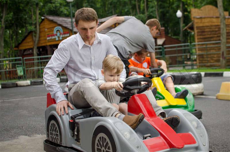 Small baby boy is enjoying driving small car in the park, stock photo