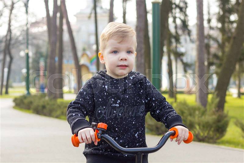 Little boy is riding a run bike and looking forward, stock photo
