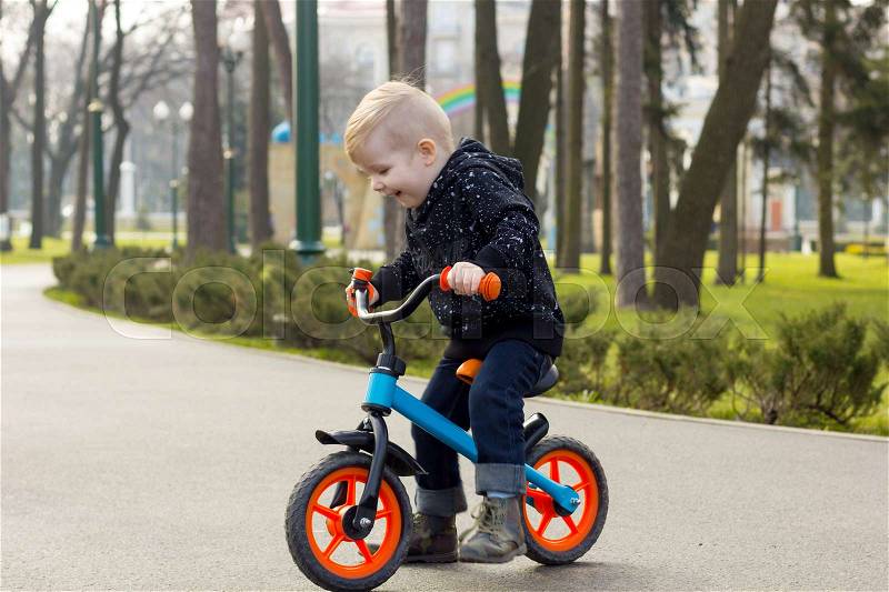 Little boy on the run bike is laughing and whatching down, stock photo