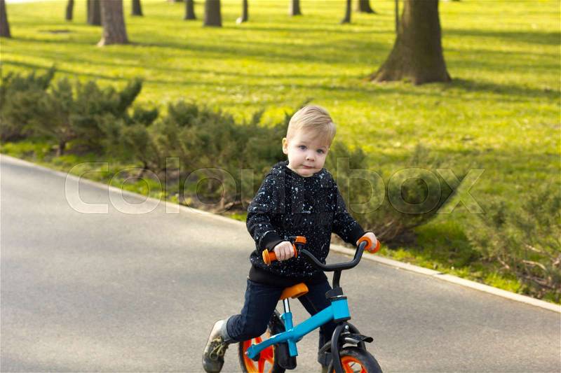 Little boy is riding orange and blue run bike, stock photo