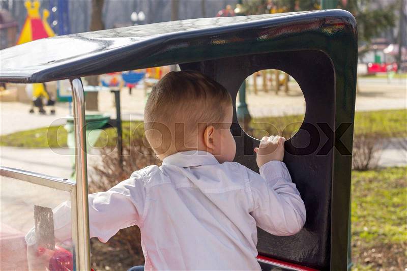 Blond boy is looking back in the toy car, stock photo