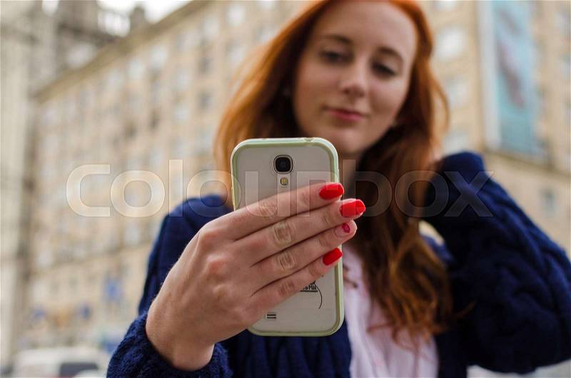 Young red woman making selfie with her cell phone, stock photo