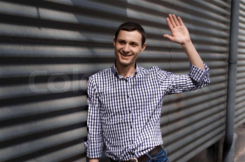 Young man says hello to friend on the street, stock photo