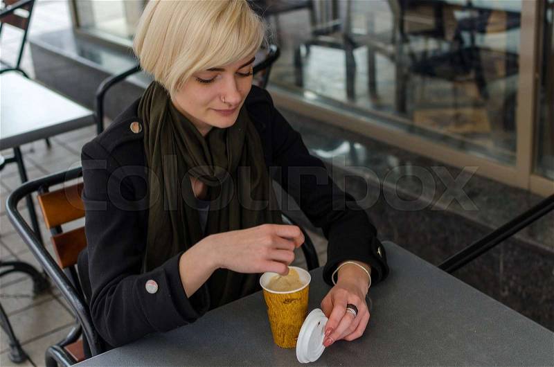 Young girl with a plastic cup of coffee walking on the cit streets, stock photo