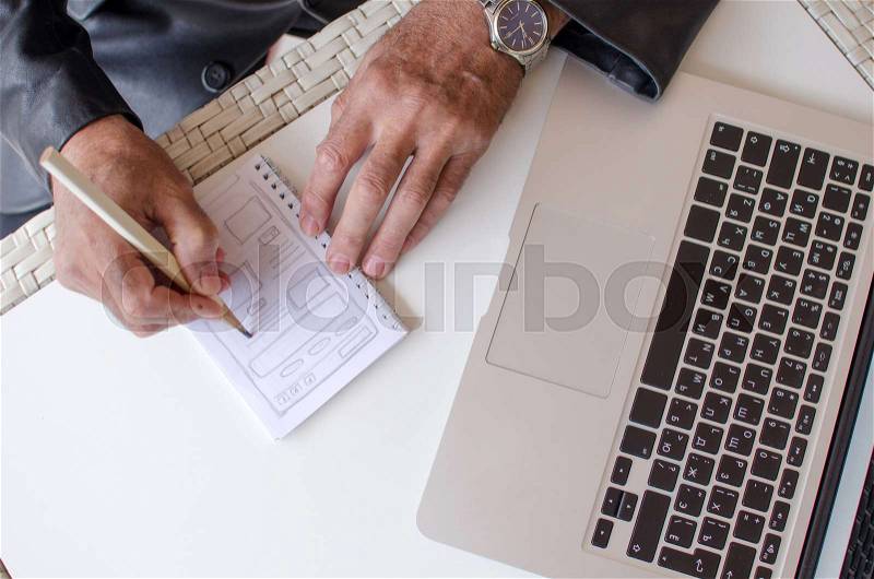 Aged man is making notes in the notebook in the park, stock photo