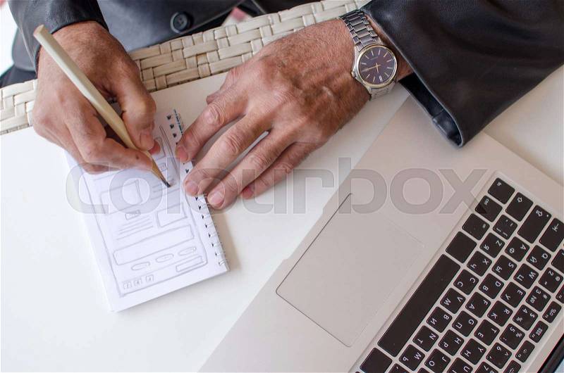 Aged man is making notes in the notebook in the park, stock photo