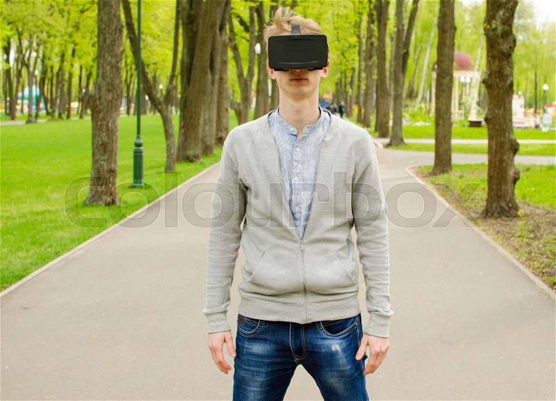 Young man using virtual glasses in the park, stock photo