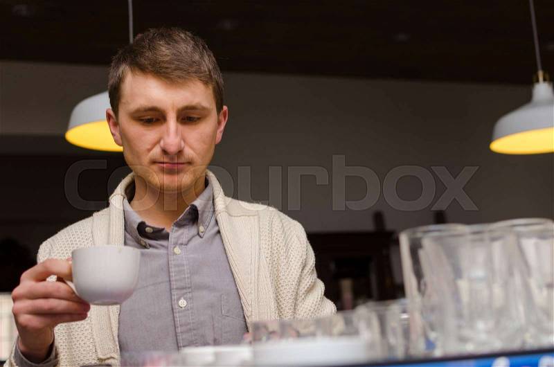Close-up photo of man drinking fresh coffee with yellow lamps on the background, stock photo