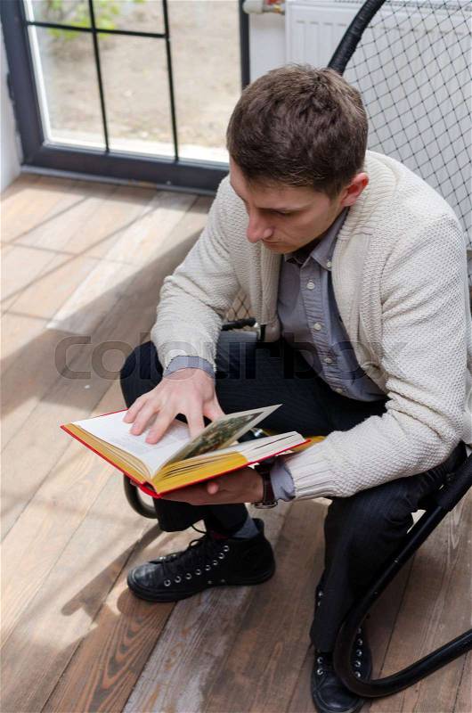 Young man turning pages in the book, stock photo