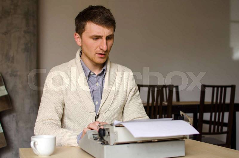 Young man is working on the typewriter, stock photo