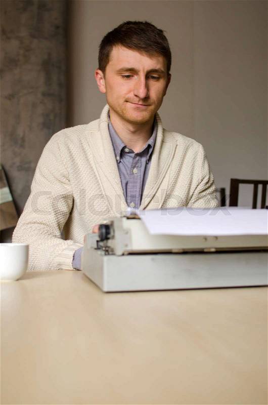 Young man is typing his ideas on the typewriter, stock photo