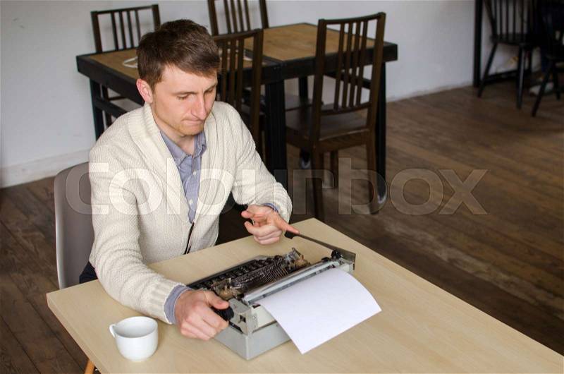 Young man is changing paper in typewriter, stock photo